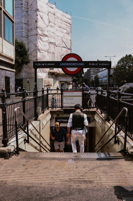 A two-storey brick building with a black painted ground floor, labeled 'Notting Hill Garage' and 'Notting Hill Garage' with white lettering and a list of services, situated on a cobblestone street in